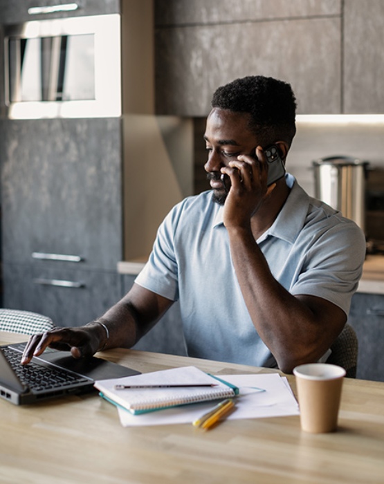 man on a mobile phone using his laptop