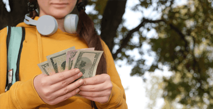 Young teen girl holding various bills of money in her hands
