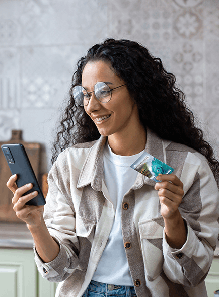 Woman looking at phone and holding credit card