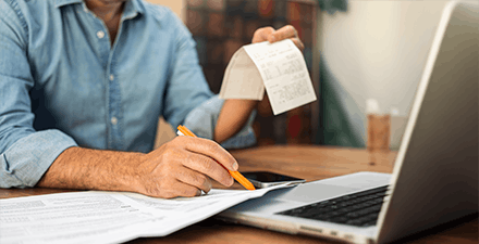 Man filling out taxes on laptop with receipts.