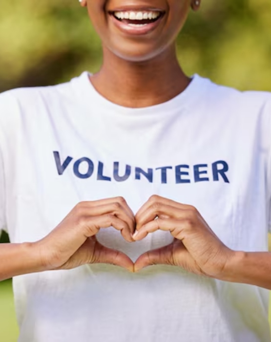 a woman showing hand hearts wearing a volunteer shirt