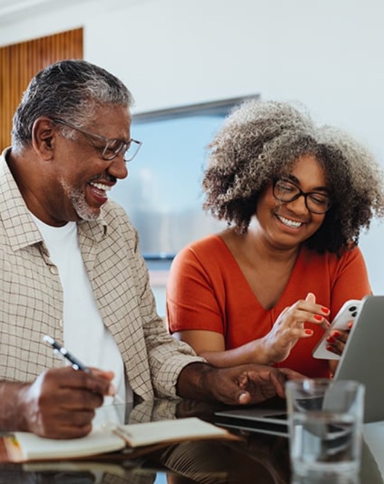 a couple taking notes while viewing their mobile phone and laptop