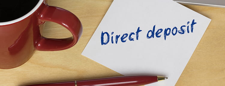 Post it note taped to desk with "Direct Deposit" written on it
