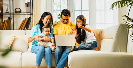 Family sitting on sofa with daughter and baby indoors