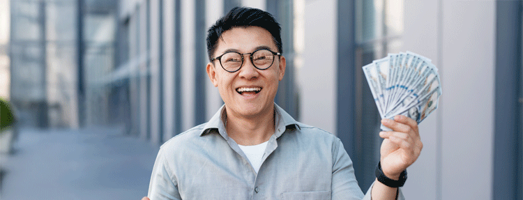 Happy middle-aged asian man holding a fan of money, celebrating financial success. Happy middle-aged asian man holding a fan of money, celebrating financial success.