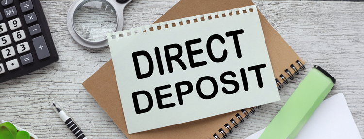 Desk with calculator and note to sign-up for direct deposit.