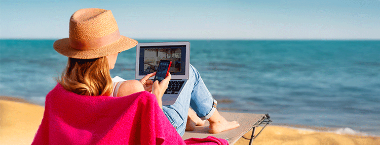 Woman working her laptop on the beach.